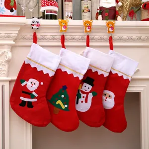 Set of large red Christmas stockings with felt appliques hanging on a white fireplace