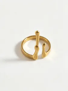Gold stainless steel ring detail shot, abstract fluid line design, minimalist jewelry close-up.