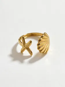 Detail view of a golden stainless steel open ring featuring a charming starfish and seashell design.