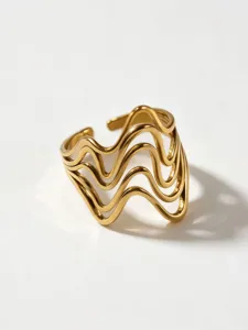 Close-up detail of multi-layer wavy geometric open ring in gold finish, modern minimalist design.