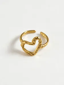 Close-up detail of modern minimalist hollow heart ring, geometric gold statement jewelry.