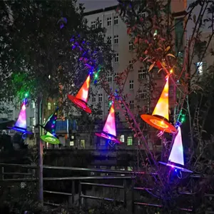 Bunte LED-leuchtende Hexenhüte für Halloween-Partydekorationen im Freien an Ästen aufgehängt