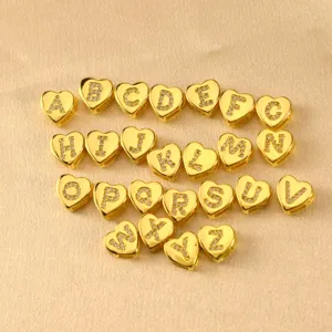 Nahaufnahme von vergoldeten Herz-Buchstaben-Anhängern, besetzt mit funkelnden Zirkonia-Steinen.