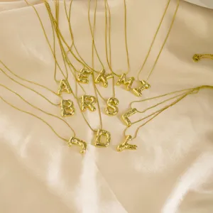 Detailaufnahme von goldenen Edelstahl Buchstaben Halsketten Anhängern mit funkelnden Strasssteinen.