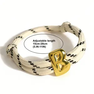 Verstellbares geflochtenes Armband Detail mit glänzendem goldenen Buchstaben B Kordel.