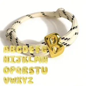 Verstellbares geflochtenes Armband mit goldenen Buchstabenanhängern für personalisierten Stil.