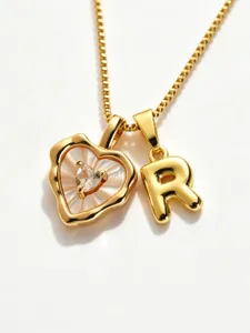 Close-up detail of gold-plated heart mother-of-pearl and letter R pendant necklace.