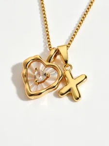 Gold tone necklace detail featuring a mother of pearl heart pendant and letter X charm close up.