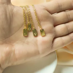 Detail shot of minimalist stainless steel gold square plate necklaces featuring engraved love letter charms.