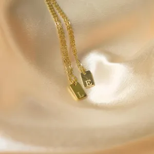 Elegant gold stainless steel necklace with rectangular initial letter pendant. Detail.