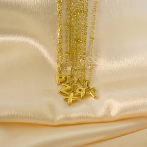 Gold stainless steel bubble letter pendant necklace detail, minimalist fashion jewelry design.
