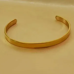 Detail shot of the minimalist gold-tone open cuff bracelet, highlighting its smooth polished finish.