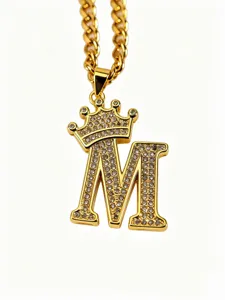 Nahaufnahme des goldenen Kronen-Buchstaben-M-Anhänger-Halskettendetails mit Zirkoniasteinen.