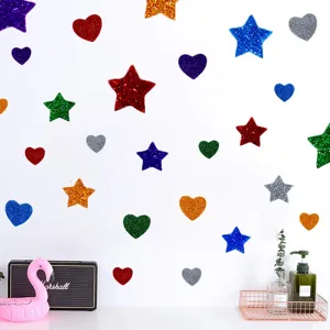 Bunte Glitzerstern- und Herz-Schaumstoffaufkleber an einer weißen Wand für DIY-Dekoration.
