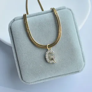 Gold snake chain necklace with sparkling zircon letter G pendant close-up detail shot jewelry display