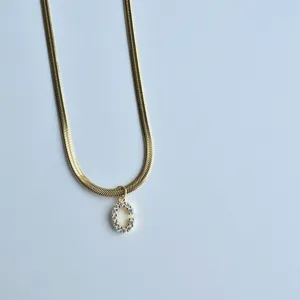 Gold herringbone chain necklace featuring a sparkling cubic zirconia letter C pendant detail.