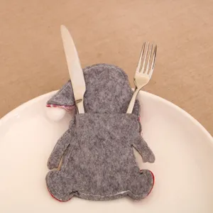 Close-up shot of gray felt gnome Christmas cutlery holder with festive red accents