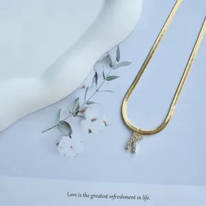 Detailed close-up of a stylish gold-plated flat snake chain necklace with a letter K pendant.