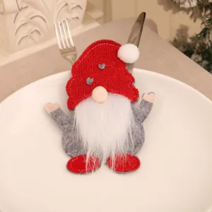 Close-up of Christmas gnome cutlery holder on white plate with silver fork and knife.