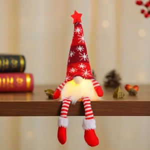 Detail van een lichtgevende kerstgnome met rode sneeuwvlokhoed en hangende benen.