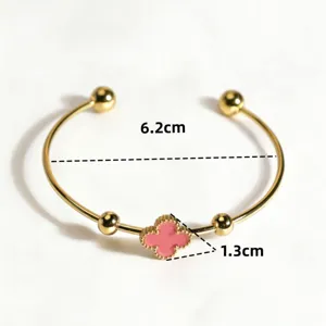 Gold open cuff bracelet featuring a pink four leaf clover charm and elegant ball ends for women