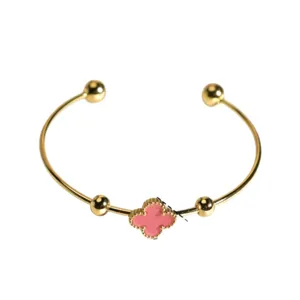 Gold open cuff bracelet featuring a chic pink clover charm and ball ends for elegant style.