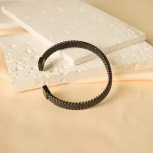 Dettaglio di bracciale aperto in acciaio inossidabile nero con trama a maglia fine.