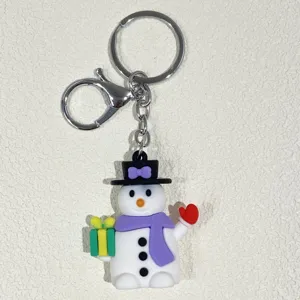 Nahaufnahme eines Weihnachts-Schneemann-Schlüsselanhängers mit lila Schal und Geschenk