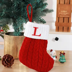 Hand-knitted red Christmas stocking with white cuff and red embroidered letter L hanging