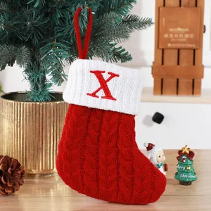 Handmade red knitted Christmas stocking with white cuff and red embroidered letter X ornament