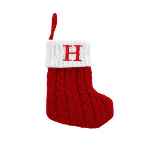 Red and white knitted Christmas stocking with embroidered letter H for tree decoration