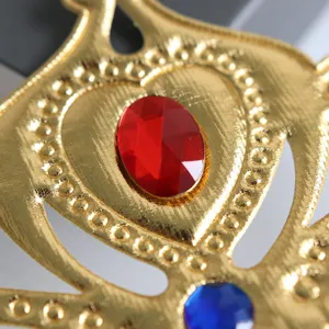 Primer plano detallado que muestra la textura y la gema roja de esta corona de tela dorada