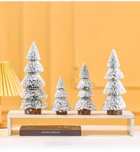 Detailed view of four mini flocked snow cedar trees arranged on a white display stand