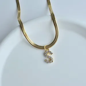 Close up of gold herringbone chain necklace featuring a sparkling zircon letter S pendant.