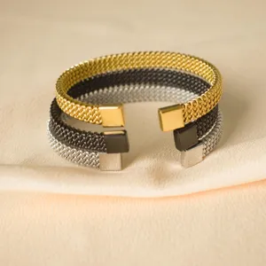 Set di tre bracciali rigidi aperti intrecciati in acciaio inox oro, nero e argento lucido.