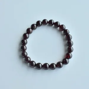 Close-up of natural stone garnet beaded bracelet detail, smooth round crystal gems.