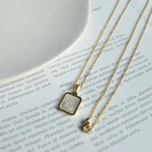 Nahaufnahme des quadratischen Perlmutt Buchstaben Anhänger Halskettendesigns in Gold.