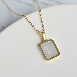 Nahaufnahme einer goldenen Halskette mit einem quadratischen Perlmutt-Buchstaben-Anhänger.