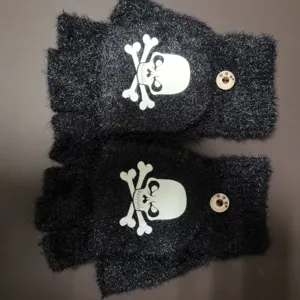 Close up of black fuzzy half finger winter gloves with skull pattern and small buttons.