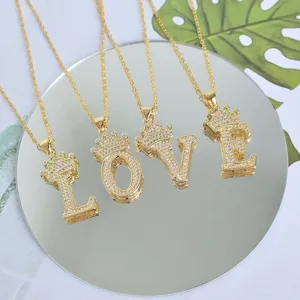 Vue détaillée de colliers de lettres dorés avec couronne disposés sur un miroir.