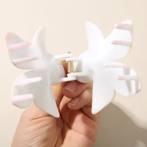 Vue détaillée d'une pince à cheveux fleur de frangipanier blanche avec pointes roses