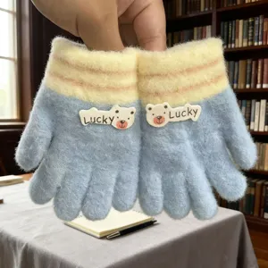 Close-up detail of cute kids knitted gloves with lovely bear patch and warm stripe design.