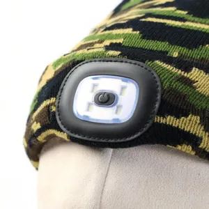 Detailopname van de LED muts met heldere aan knop voorzijde op camo gebreide stof.