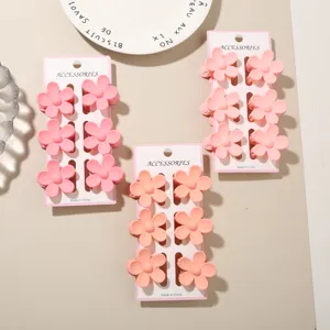 Close-up detail of three 6-piece flower hair claw clip sets in pink and peach colors
