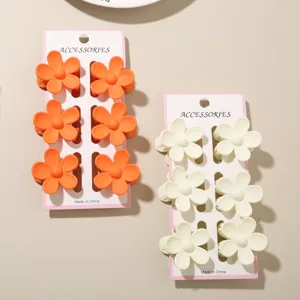 Detail view of 6-piece matte flower hair claw sets in vibrant orange and cream white colors