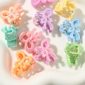 Dettaglio delle mollette per capelli a farfalla perlate da 2,7 cm in colori pastello.