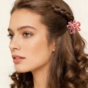 Dettaglio laterale di una mini molletta per capelli a fiore rosa su capelli castani mossi