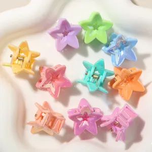 Primo piano di mini fermagli per capelli colorati a forma di stella in vari toni.