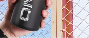 Nahaufnahme einer Hand, die eine elegante mattschwarze Sport-Wasserflasche im Freien hält