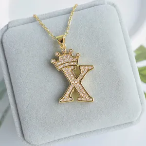 Vue rapprochée détaillée du collier pendentif strass lettre X couronne dorée brillante.